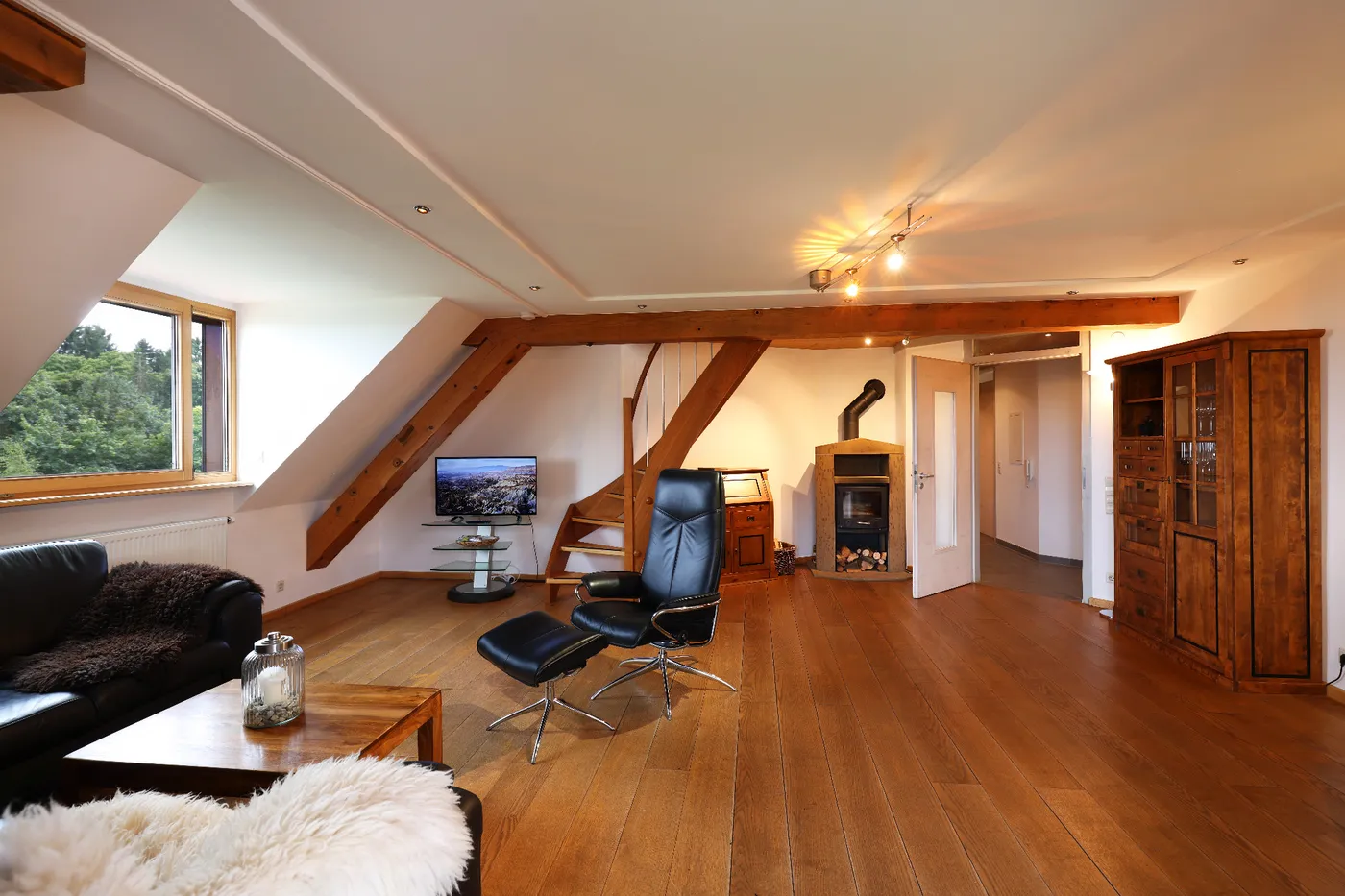 Wohnzimmer der Ferienwohnung mit Dachbalken, Kaminofen und Sofa