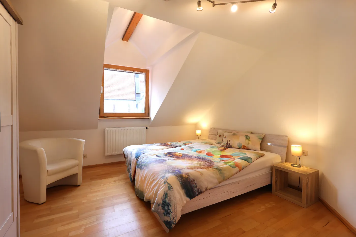 Schlafzimmer mit Doppelbett und Sessel unter der Schräge