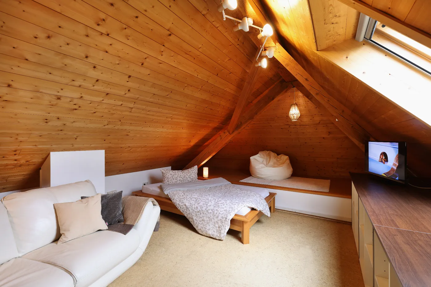 Schlafbereich mit Holzdecke und Sofa