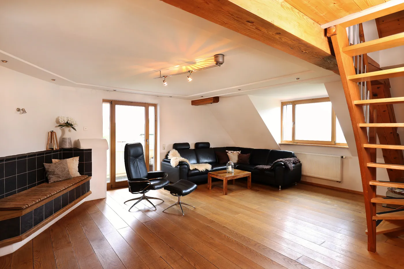 Wohnbereich mit Ledersofa, Sessel und Holztreppe